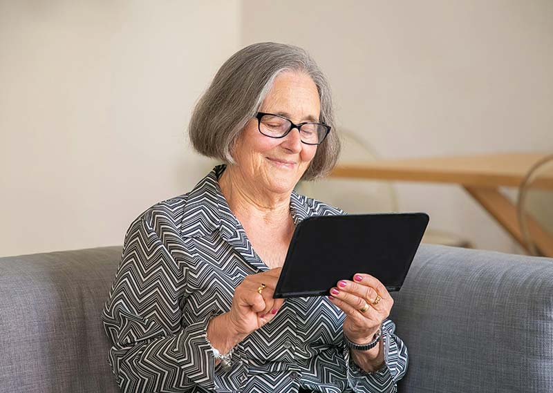 Une personne âgée consulte une tablette numérique