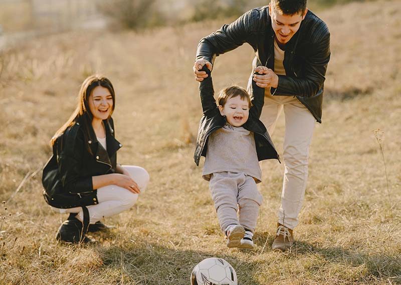 Un couple joue au ballon avec son enfant